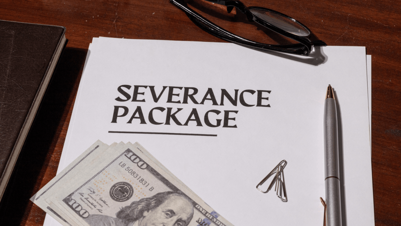 Employment settlement severance package documents with cash and pen on desk