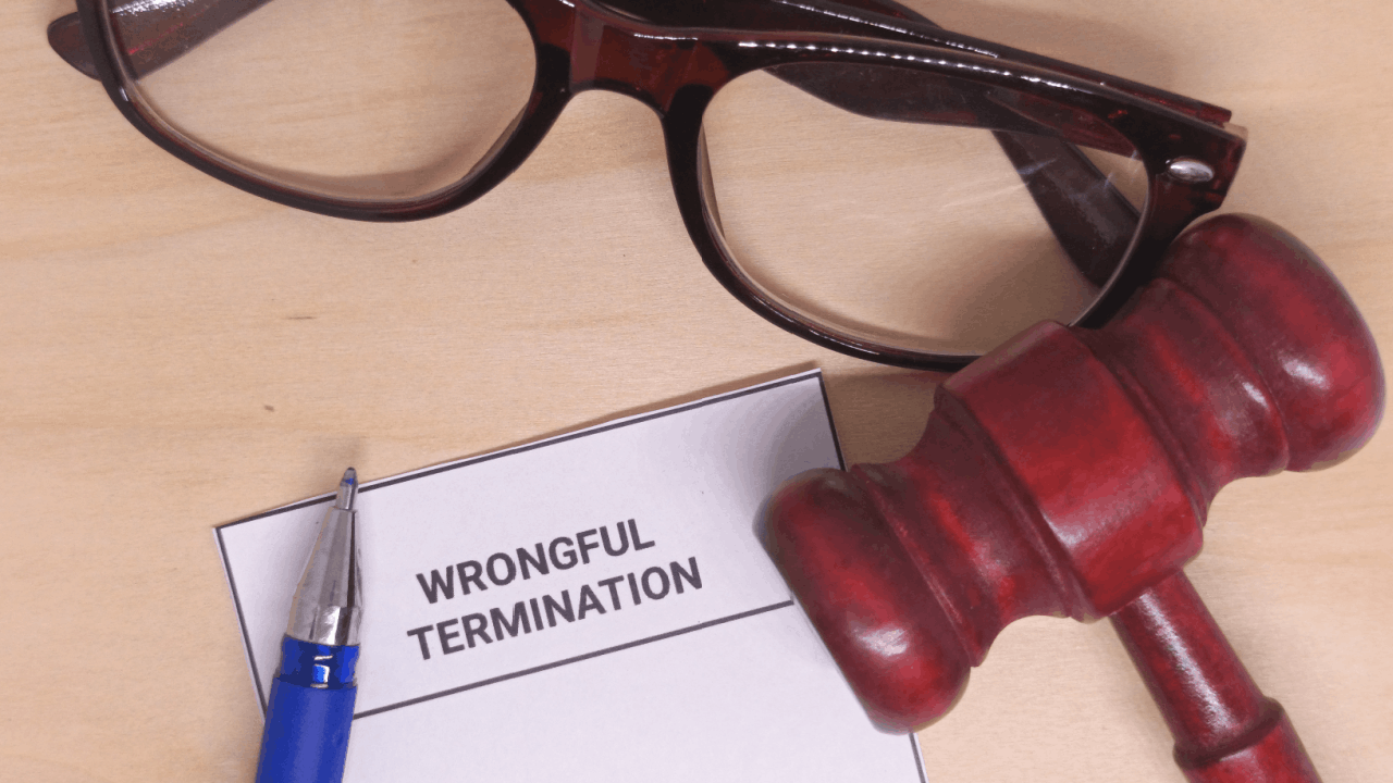 Wrongful termination document with gavel and glasses on a desk